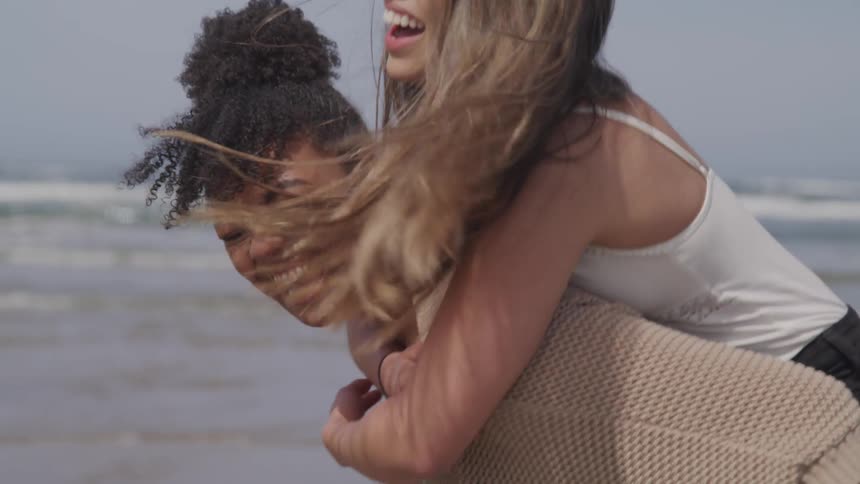 Two women are laughing and having fun at the beach