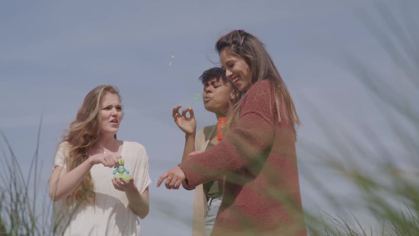 Three teens bubbles together outside