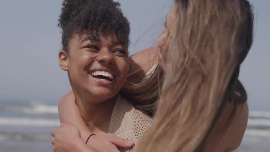 One girl gives her friend a piggyback and they both laugh