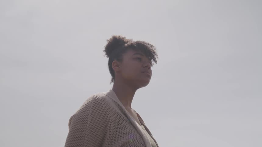 A woman is walking outside while wearing a sweater