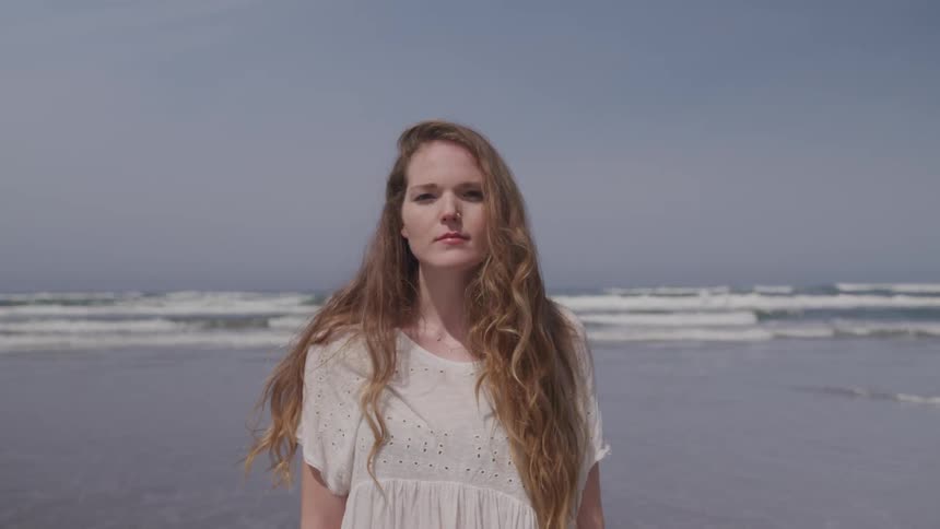 A woman is standing by the ocean