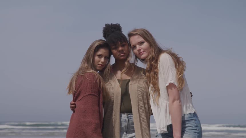 Three teenage friends pose on the beach