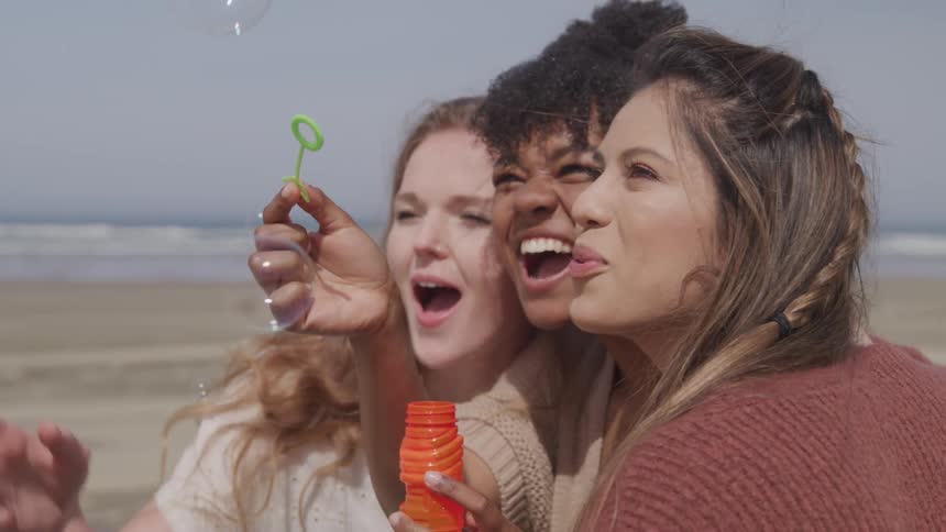 Laughing women bubbles outdoors at the beach