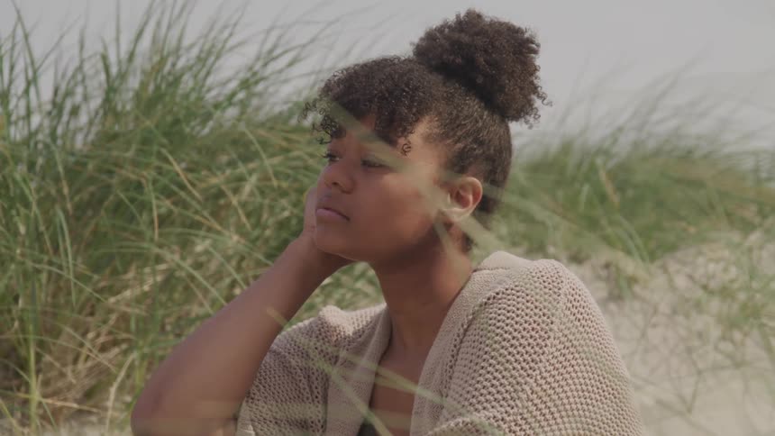 A black woman sitting on the grassfield