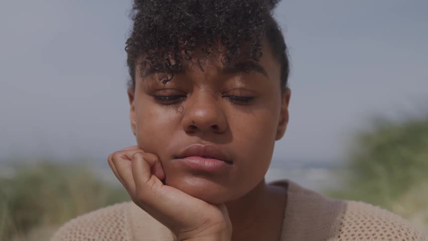 A young woman resting her chin in her palm while looking into the camera