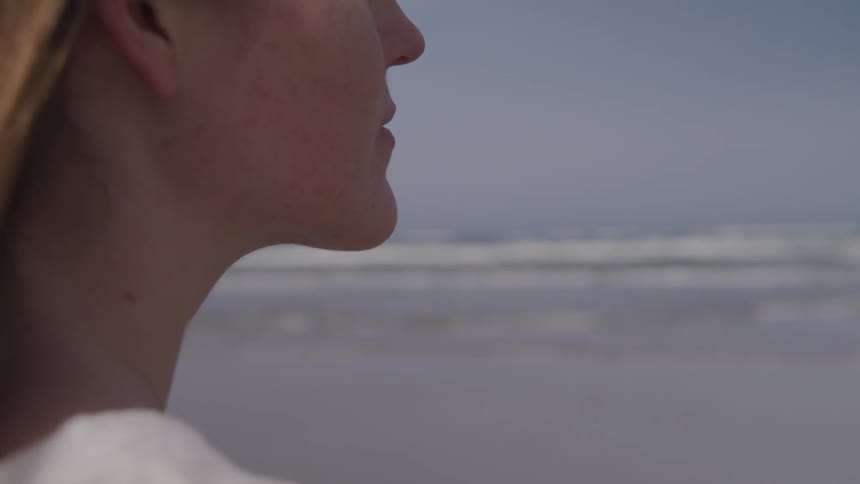 A woman is watching the beach on a cloudy day