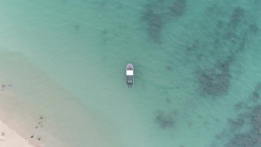 Birds eye view of a beach and a boat in the water