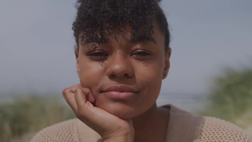A woman stares into the camera and smiles
