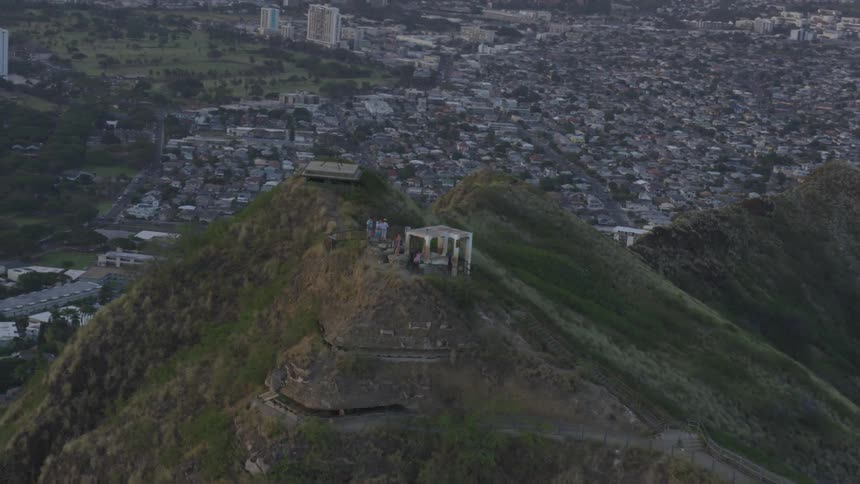 A single estate sits on top of a large mountain overlooking a city
