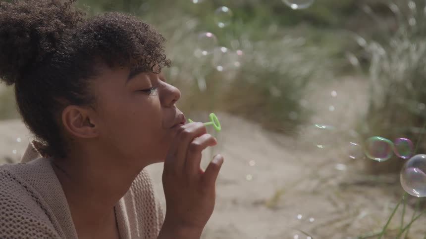 A woman is blowing bubbles outdoors