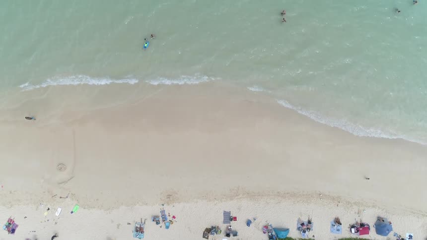 People relax on the beach and play in the clear ocean waters at this lovely beach