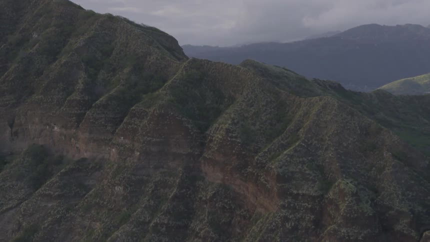 Aerial view of big mountain range with distant located city on a cloudy day