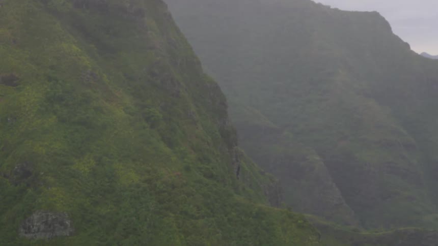 Rocky ocean side cliffs covered in brush on a cloudy day