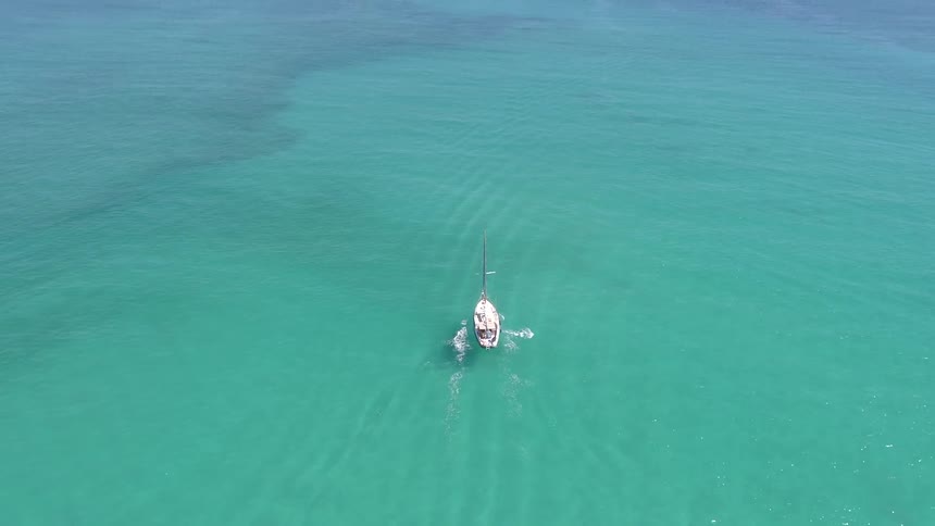 Sailboat travels in the blue ocean under a sunny sky