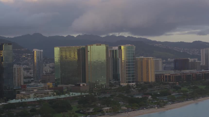 City stands between mountain range and the ocean under heavy dark clouds