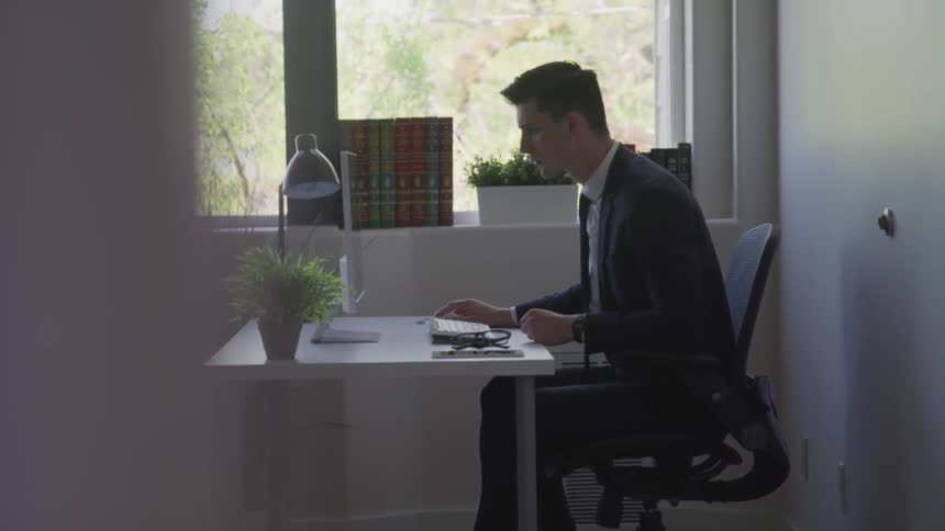 Businessman in a suit sitting at the desk uses computer in the office