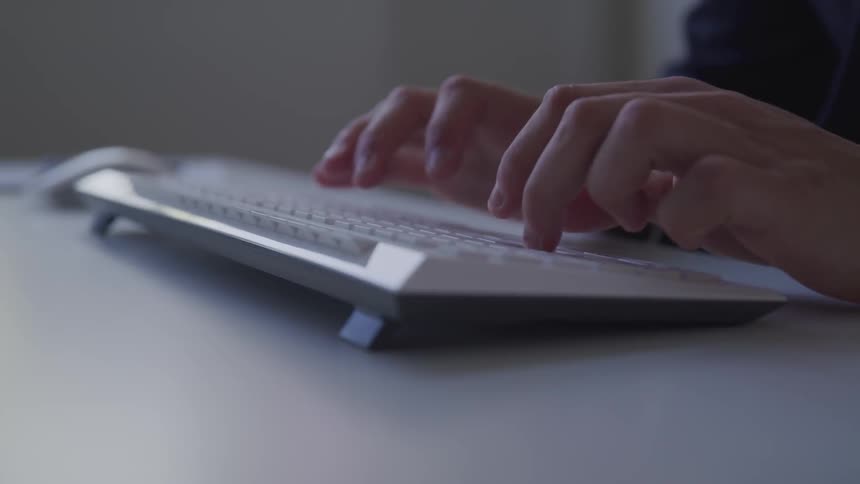 Hands typing on a computer keyboard on a desk