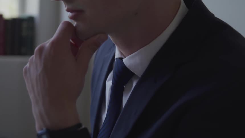 Pensive man in a business suit resting chin resting on his hand