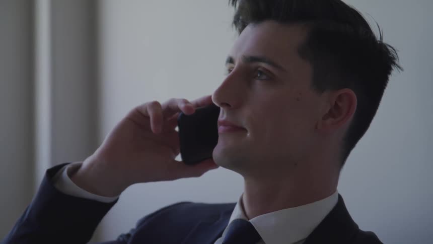 Businessman in the suit talks to someone on the phone in the office