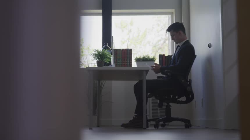 A young man sits at his desk and uses his phone
