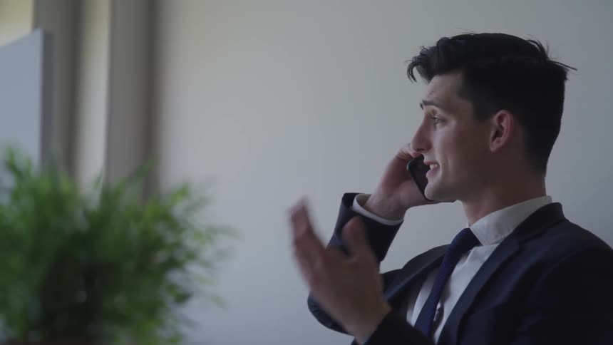 Man is talking on a cellphone while wearing a suit
