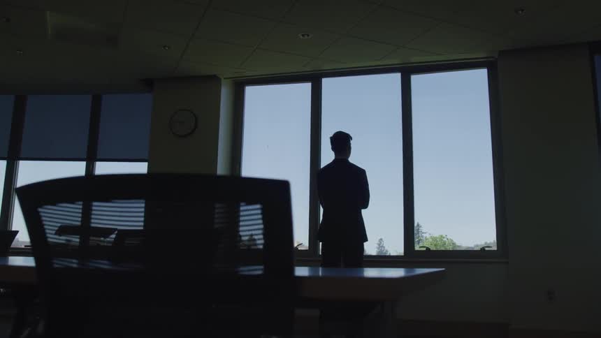 A young man looks out of an office window