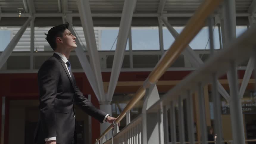A man is holding a railing and looking up