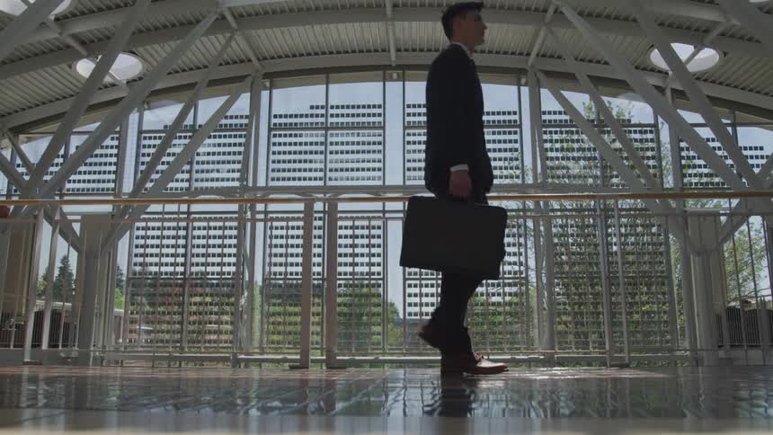 A man carrying a briefcase walks across a building lobby