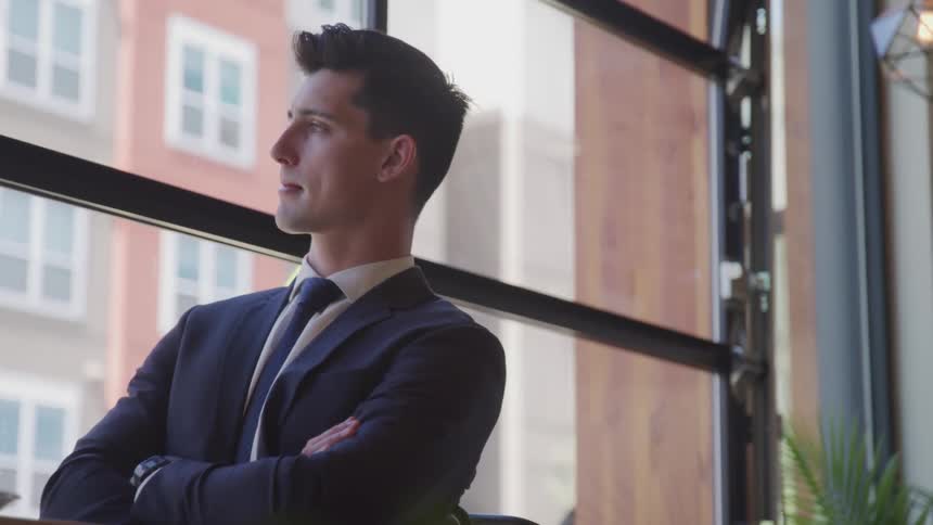 Anxious young man with crossed arms looking out office window