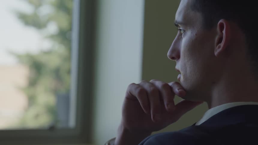 Businessman sitting on the chair looks out the window in the office