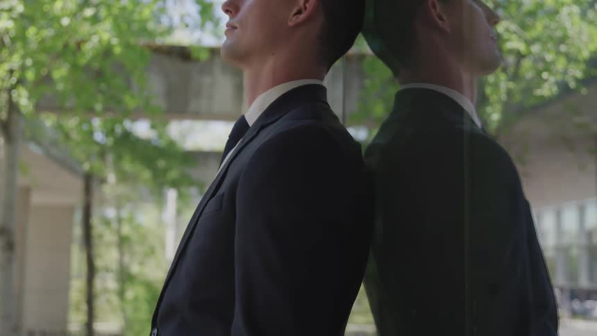 A man leans against a window with his eyes closed