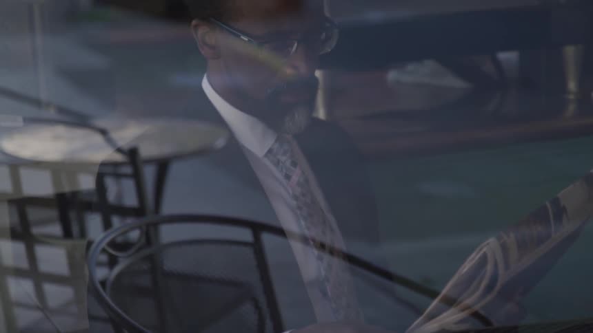 Black businessman sitting at the table reads a newspaper in the cafe