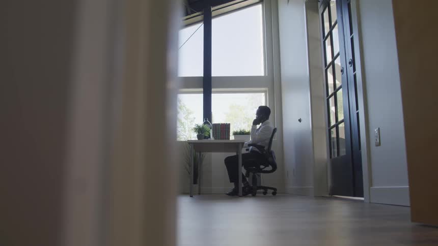A man is sitting in an office and talking on the phone