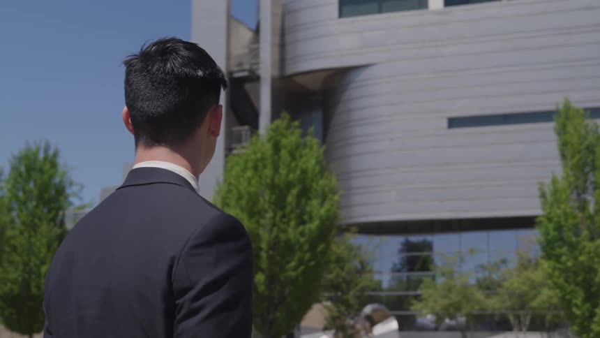 A man in a suit looks to a large building