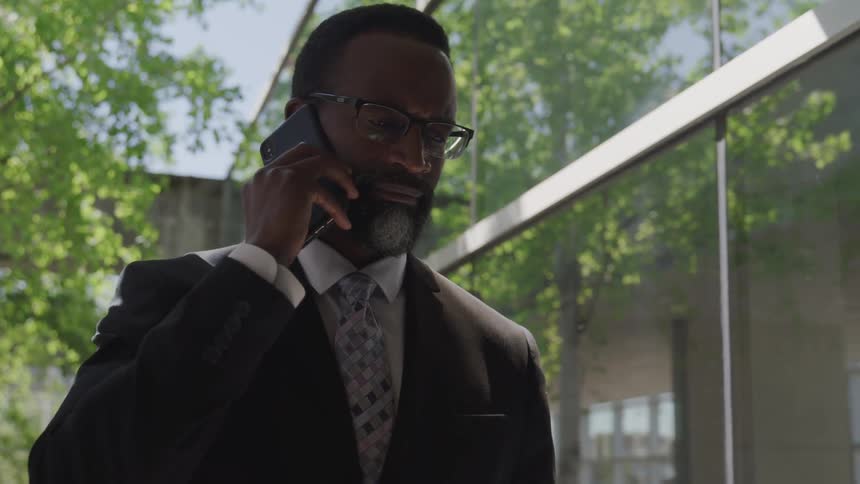 A man is talking on a cellphone and standing outside