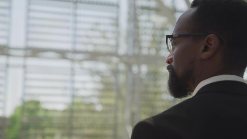 Blackman looks to the left as he stands in front of a window