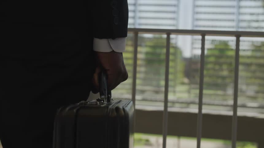 A man is carrying a briefcase by the railing