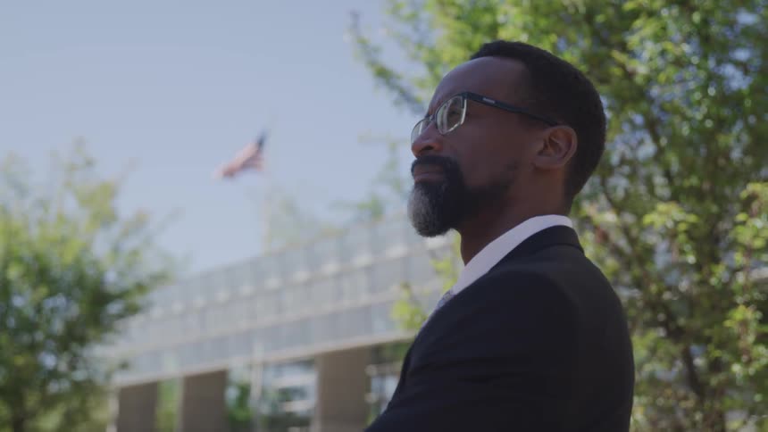 A man looking into the distance in front of a building