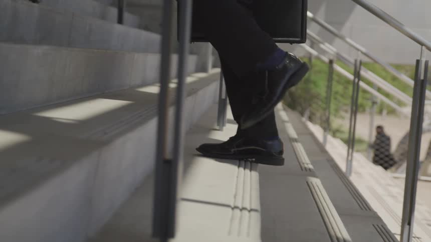 Businessman walking up stairs outdoors while carrying a briefcase