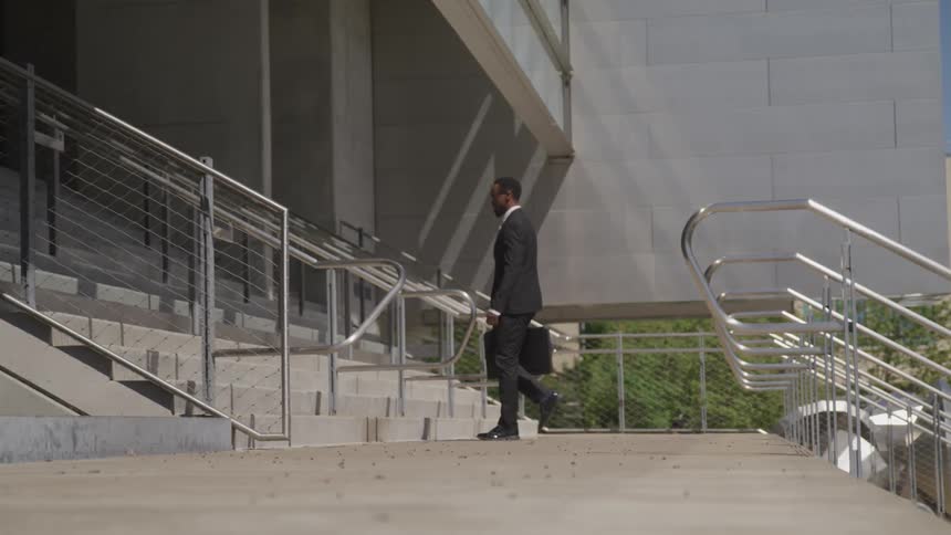 A man is holding a suitcase and walking into a building