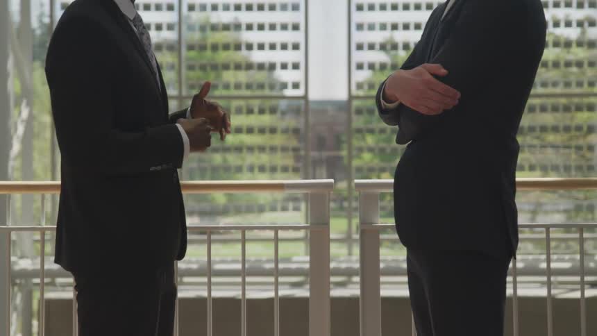 Two men stand inside and talk