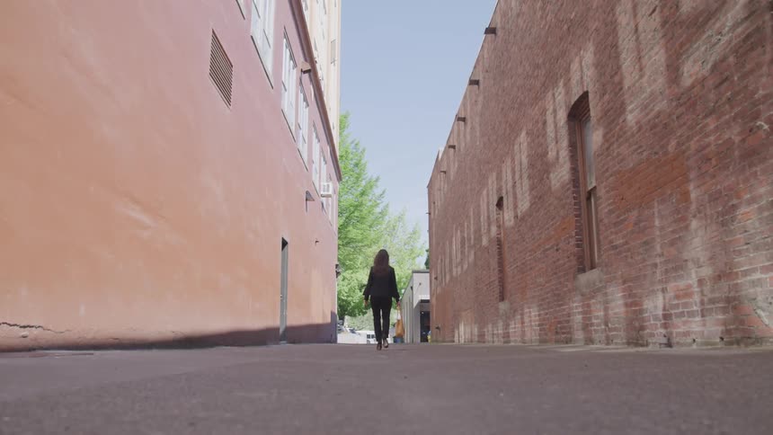 A young woman walks between two buildings