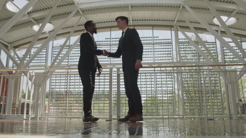Two men walk towards each other and shake hands