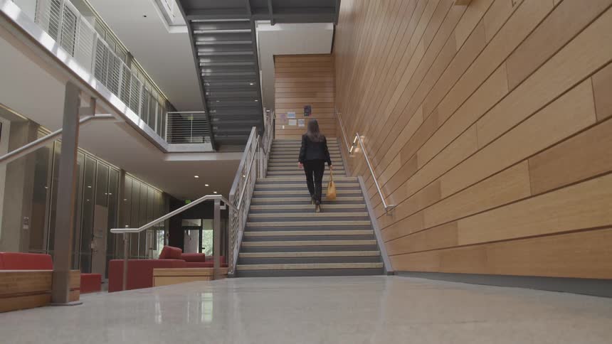 A woman walks up a flight of stairs in an office building