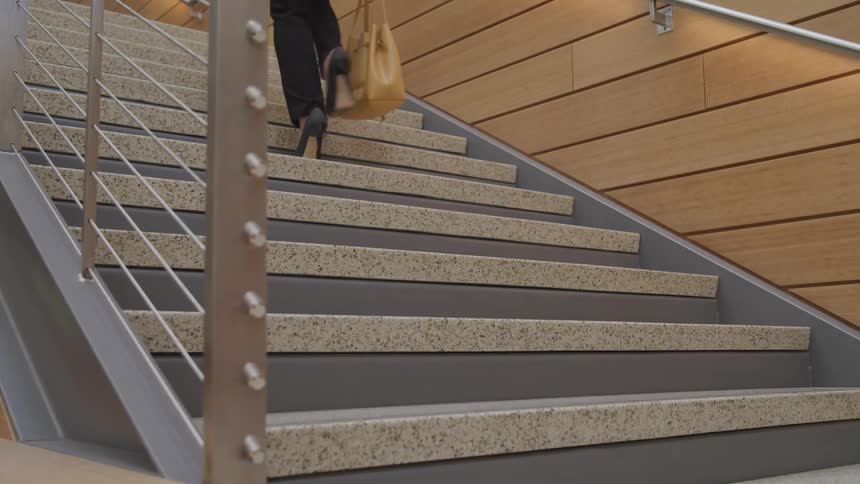 A woman climbs a staircase holding her purse