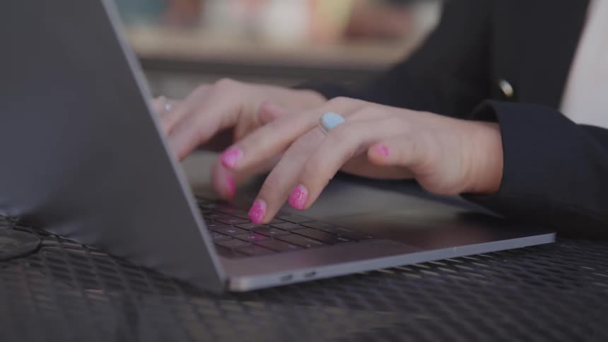 Woman in business suit types on laptops at table