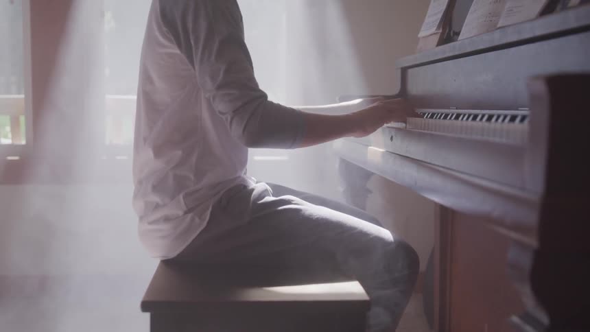 A man plays a piano in a sunny room
