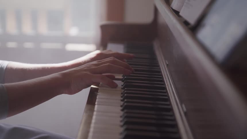 A person playing the piano indoors during the day