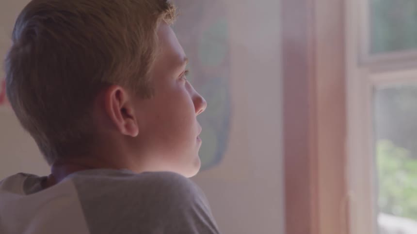 A boy stare to outside of the window
