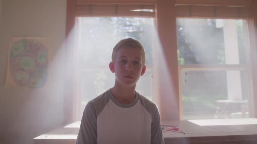 A young boy sits in front of a window